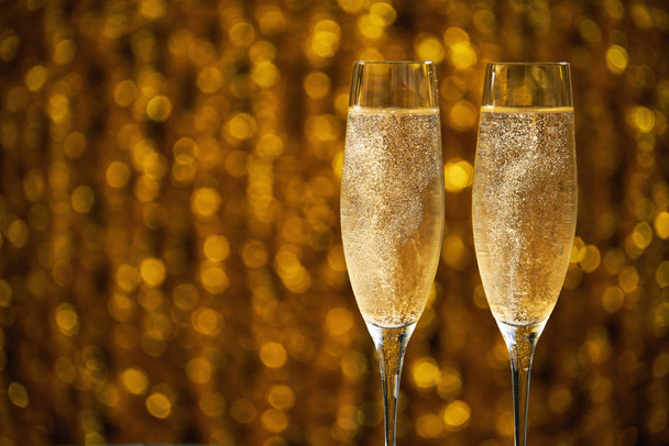Dvě skleničky šampaňského na zlatém pozadí - Fotografie, Obrázek