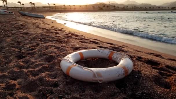 4k felvétel az élet-megtakarítás gyűrűt feküdt a homokos tengerparton naplementekor - Felvétel, videó