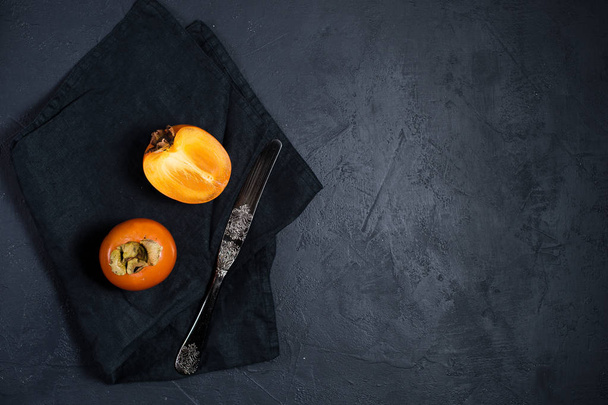 Ripe persimmon, knife on black background with space for text. - Φωτογραφία, εικόνα