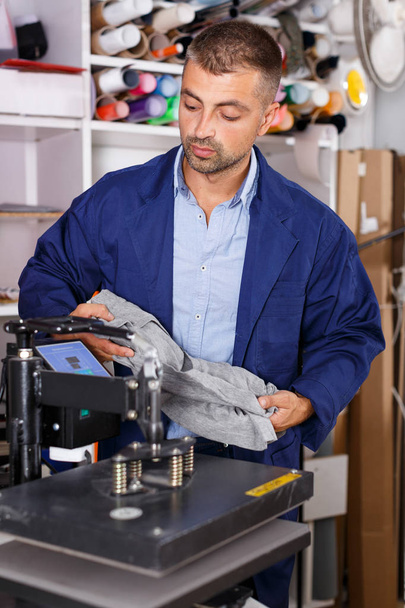 male worker makes print on shirt - Photo, Image