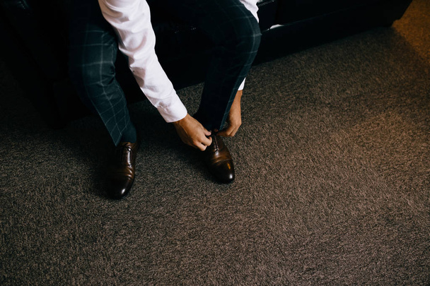 Элегантный мужчина надевает черную, кожаную, формальную обувь. Завязывание обуви
 - Фото, изображение