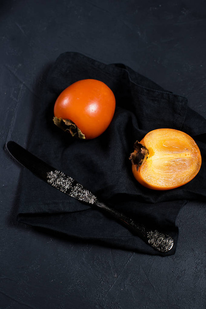 Persimmon on black fabric with space for text. - Photo, Image