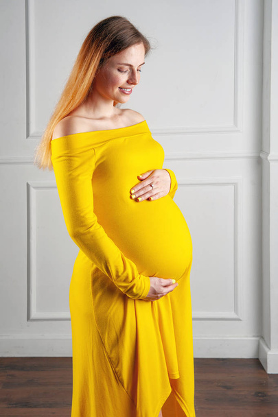 Happy pregnant woman with hands on her big belly - 写真・画像