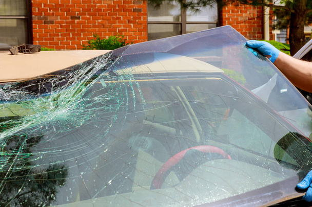 Workers remove crashed windshield of a car in auto service - Photo, Image