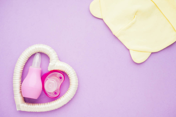 Newborn baby story. Strow heart and children's toys, scissors, baby bottle, nipple, hairbrush on violet background - Φωτογραφία, εικόνα