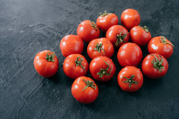 Biologische groenten en gezond eetconcept. Geoogst rode tomaten met water druppels, zwarte achtergrond. Close-up textuur. Openluchtmarkt - Foto, afbeelding
