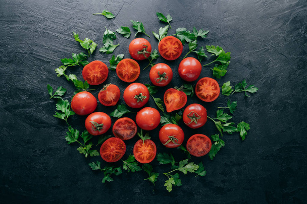 Σφηνάκι κόκκινες ώριμες ντομάτες και πράσινο φρέσκο μαϊντανό σε σκοτεινό φόντο. Σύνθεση λαχανικών. Υγιεινή διατροφή έννοια. Βιολογικά τρόφιμα - Φωτογραφία, εικόνα