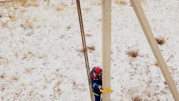 Elektricien in overalls en helm klimmen naar de spannings paal - Video