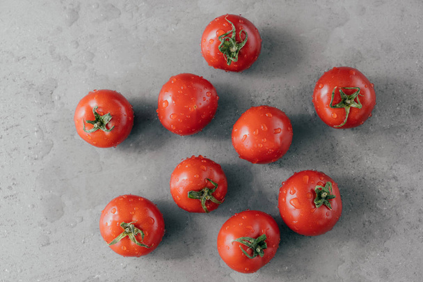 Close-up tiro de tomates heirloom vermelho cravejado com gotas de água contra fundo cinza. Legumes frescos. Tiro horizontal
. - Foto, Imagem