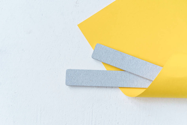 gray nail file wrapped in yellow paper - Φωτογραφία, εικόνα