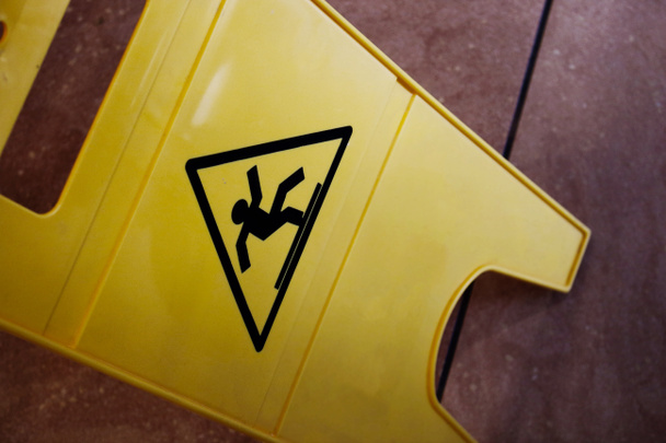 Signo de precaución amarillo resbaladizo piso en baldosas vista superior hacia abajo
 - Foto, imagen