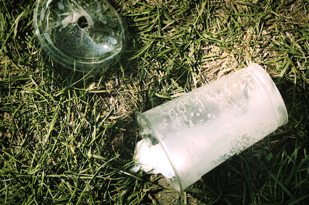 Used plastic cup left on green grass lawn environment - Photo, Image