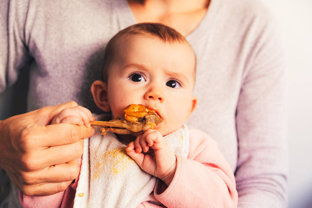 4 miesiąca życia dziecko gryząc udko z kurczaka, jego pierwszy potrawy degustacja - Zdjęcie, obraz