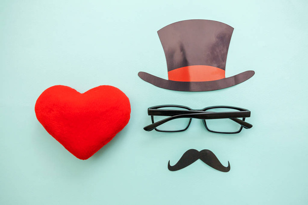 Happy Father's day concept. Sign of hat mustache with glasses red heart isolated on pastel blue background - Photo, Image