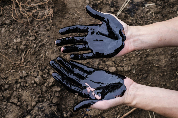 oil leaking. Very dirty hand.Stain hands showing thumbs up with black oil on soil background. - 写真・画像