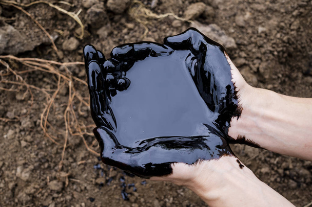 oil leaking. Very dirty hand.Stain hands showing thumbs up with black oil on soil background. - Φωτογραφία, εικόνα