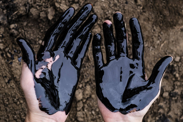 oil leaking. Very dirty hand.Stain hands showing thumbs up with black oil on soil background. - Φωτογραφία, εικόνα