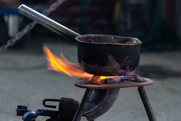 クローズアップ金属鍋は、鉛の金属製錬ワークショップでガスバーナーで加熱されます。ガスバーナーの鍋で食べ物を調理する旅行オプション。鉄鋼業 - 写真・画像