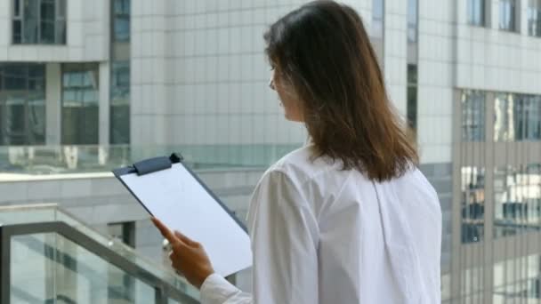 Pretty businesswoman draws  scheme on sheet of paper.ity area, steady shot - Filmmaterial, Video