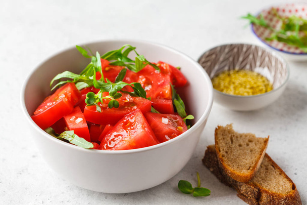 Tomatoes and arugula salad with sprouts and olive oil in gray bo - Φωτογραφία, εικόνα