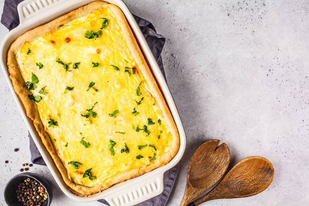 Quiche with cheese and greens in a black baking dish. - Foto, afbeelding