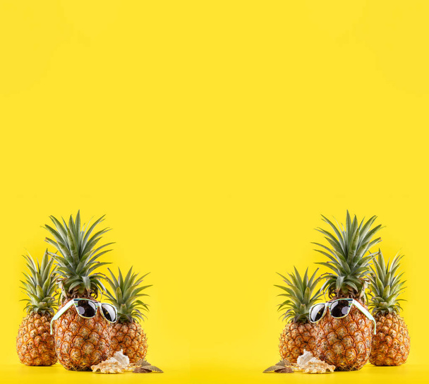 Creative pineapple looking up with sunglasses and shell isolated on yellow background, summer vacation beach idea design pattern, copy space close up - Fotografie, Obrázek