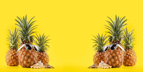 Creative pineapple looking up with sunglasses and shell isolated on yellow background, summer vacation beach idea design pattern, copy space close up - Fotoğraf, Görsel