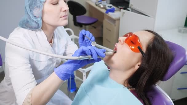 Nuori nainen hammaslääkärin hammastuolin ennaltaehkäisevässä tarkastuksessa. Hampaiden hoito käsite
. - Materiaali, video