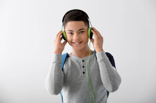 灰色の背景にヘッドフォンを持つアフリカ系アメリカ人の十代の少年の肖像画 - 写真・画像