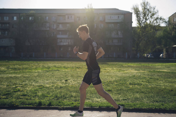 The athlete jogs in headphones on the lawn - Valokuva, kuva