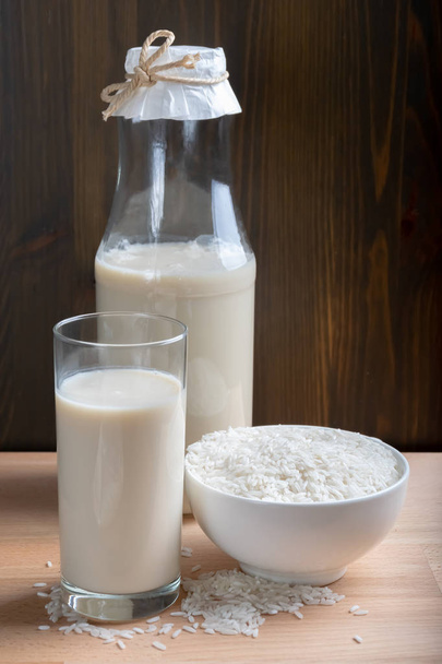 Rice milk in glass and organic rice on wooden background, Alternative Milk - Foto, Imagem