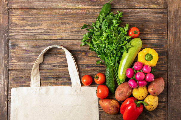 木製の背景に綿のショッピングバッグと新鮮な素朴な野菜。エココンセプト。スペースをコピーします。フラットレイアウト. - 写真・画像
