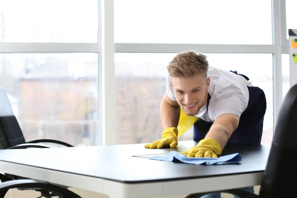 Hausmeister putzt Tisch im Büro - Foto, Bild
