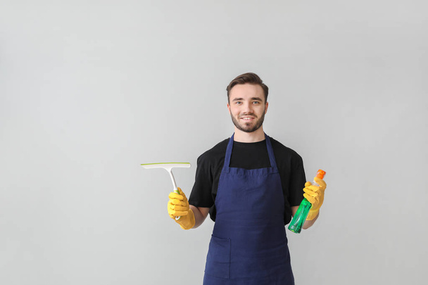 Miespuolisen talonmiehen muotokuva siivoustarvikkeilla kevyellä taustalla
 - Valokuva, kuva