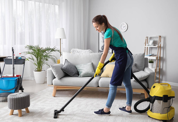 Female janitor with vacuum cleaner in room - Фото, зображення