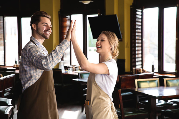 Junge Kellner geben sich gegenseitig High-Five im Restaurant - Foto, Bild
