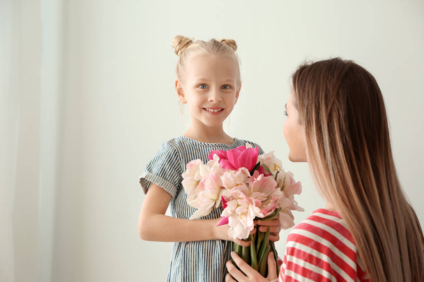 Mała dziewczynka powitanie jej matka z bukiet tulipany w domu - Zdjęcie, obraz