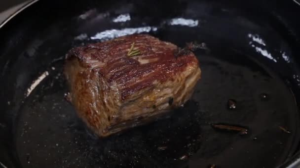 Velký steak se smažuje v pánvi v kuchyni v restauraci v těsné blízkosti - Záběry, video
