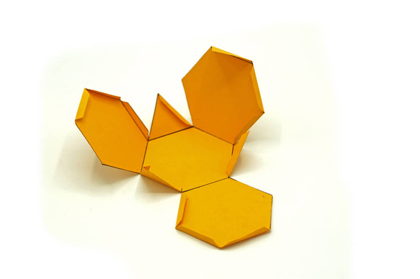 Geometrik şekil sarı kağıttan kesilmiş ve beyaz arka plan üzerinde fotoğraflandı. Kesilmiş tetrahedronun geometri ağı. Açılmamış üç boyutlu figürler. - Fotoğraf, Görsel