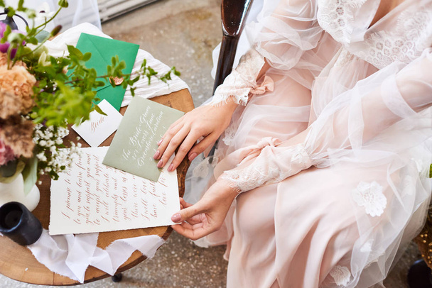 ピンクベージュのパステルカラーのぼやけた画像は、朝、花嫁は手紙の書道を読みます。ブドワール写真。選択フォーカス - 写真・画像