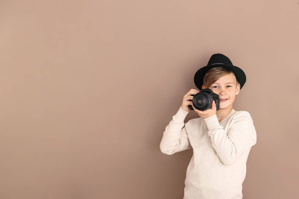 Cute little photographer with professional camera on color background - Foto, afbeelding