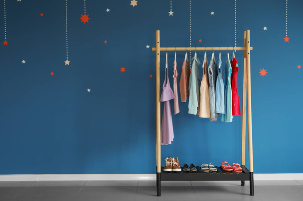 Rack with children's clothes near color wall - Foto, imagen
