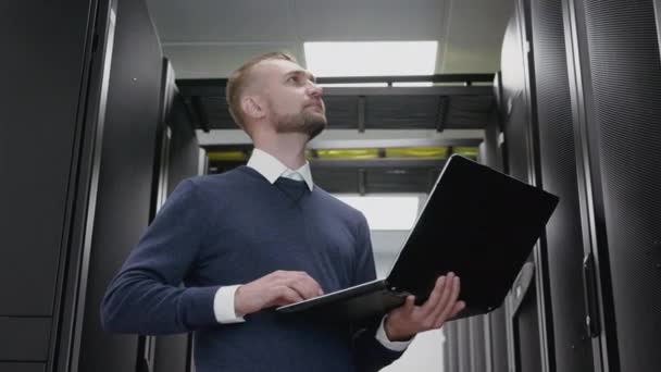Człowiek trzyma laptopa i zrobić diagnostykę Datacenter w serwerowni - Materiał filmowy, wideo