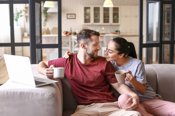 feliz jovem casal com laptop beber chá em casa
 - Foto, Imagem