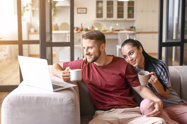 Heureux jeune couple avec ordinateur portable boire du thé à la maison
 - Photo, image