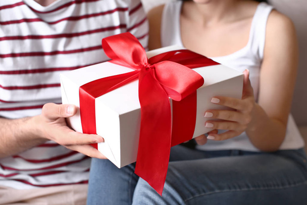 Happy young couple with gift at home, closeup - Photo, image