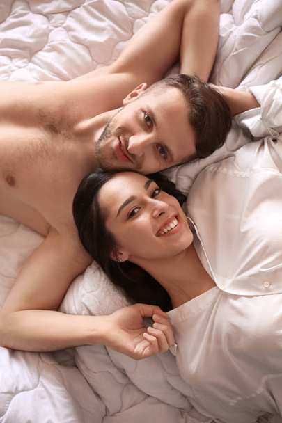 gelukkige jonge paar liggend op bed - Foto, afbeelding
