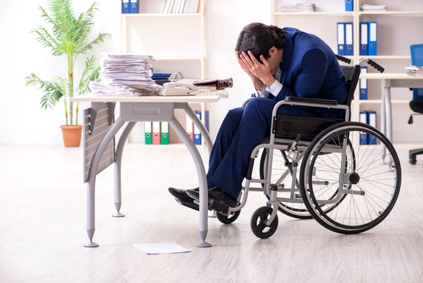 Young male employee in wheelchair working in the office  - Фото, изображение