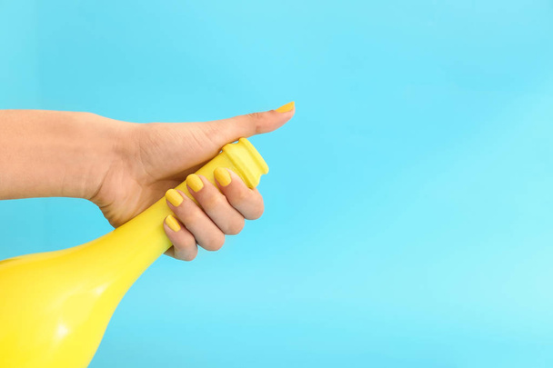 Θηλυκό χέρι με κομψό μανικιούρ και μπουκάλι στο χρώμα φόντο - Φωτογραφία, εικόνα