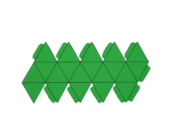 Geometrische vorm gesneden uit papier en gefotografeerd op witte achtergrond. Geometrie netto van Platonische lichamen icosaëder. 2-dimensionale vorm die kan worden gevouwen om een 3-dimensionale vorm of een vaste. - Foto, afbeelding